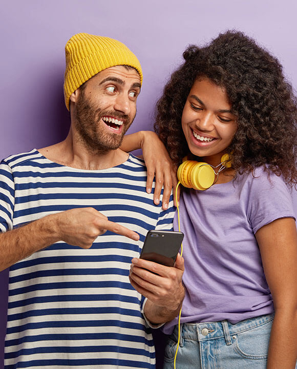 A man with a yellow tuque showing his friend something on mobile